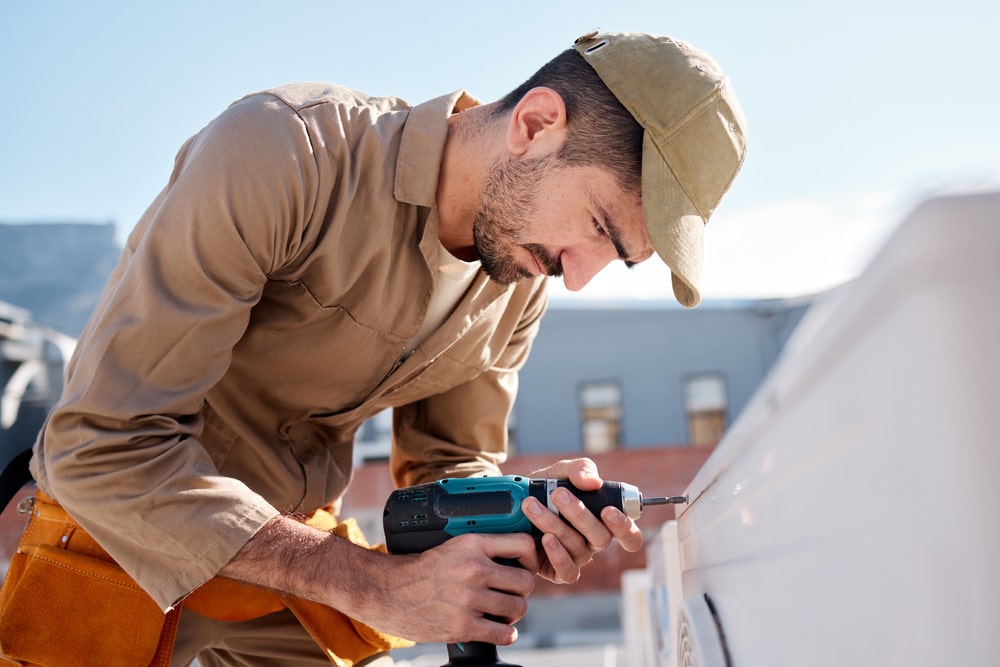 technician drill an outdoor air conditioner